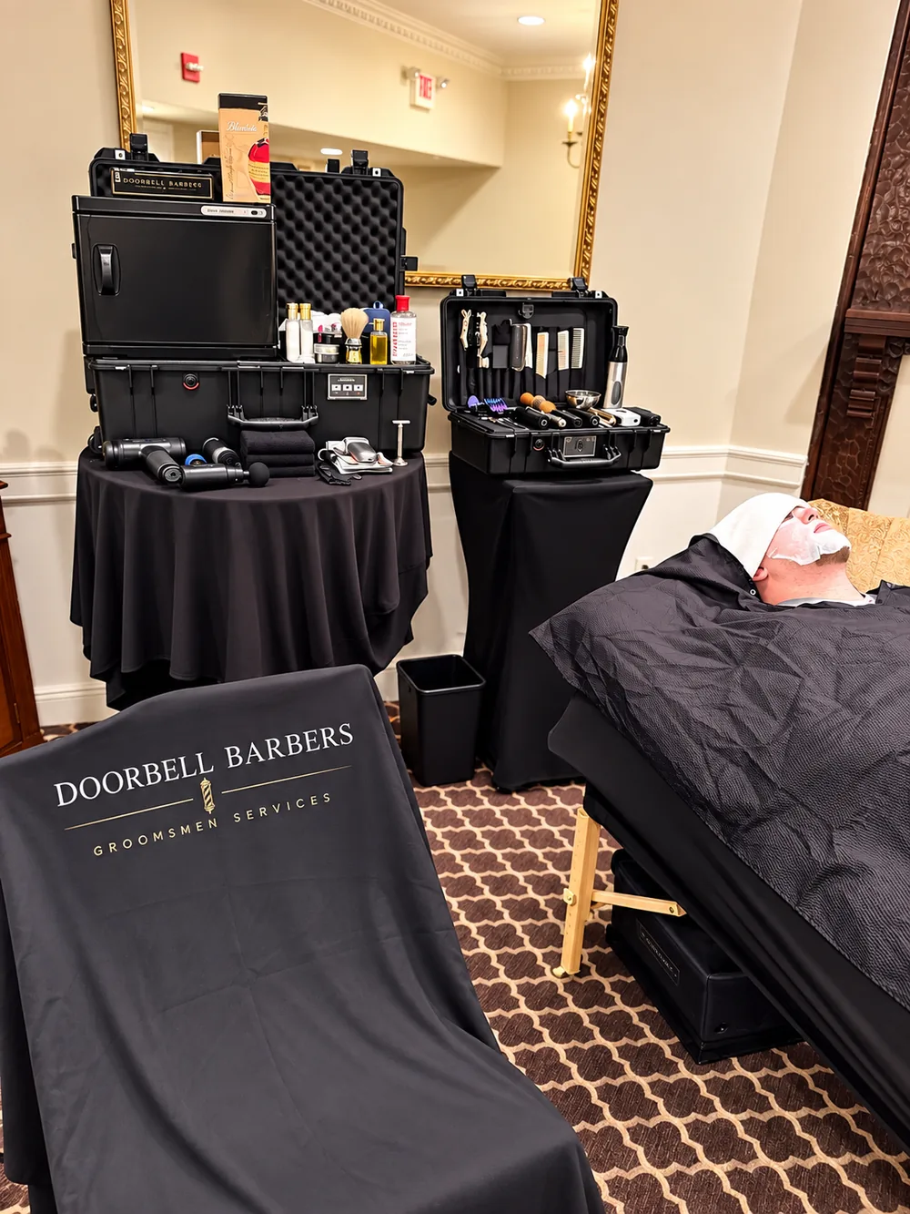 Doorbell Barbers wedding-morning setup with barber kits and a groomsman under a hot towel on a tilt massage table