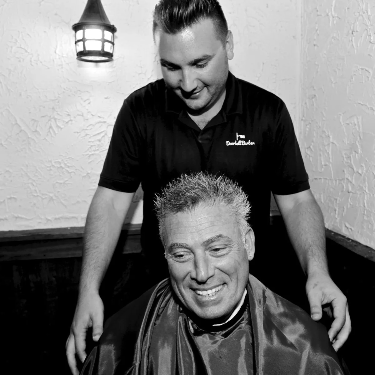 Professional Doorbell Barbers barber smiling with a senior client in a barbershop setting