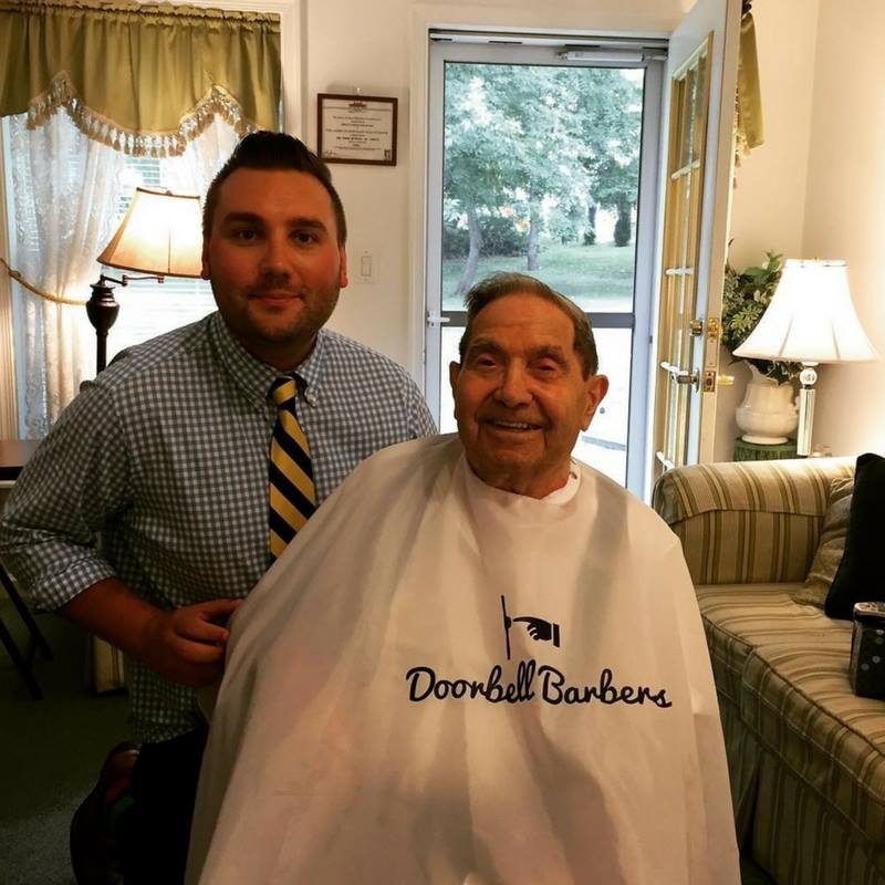 Christian Iannucci with a senior client in a Doorbell Barbers cape during an in-home haircut