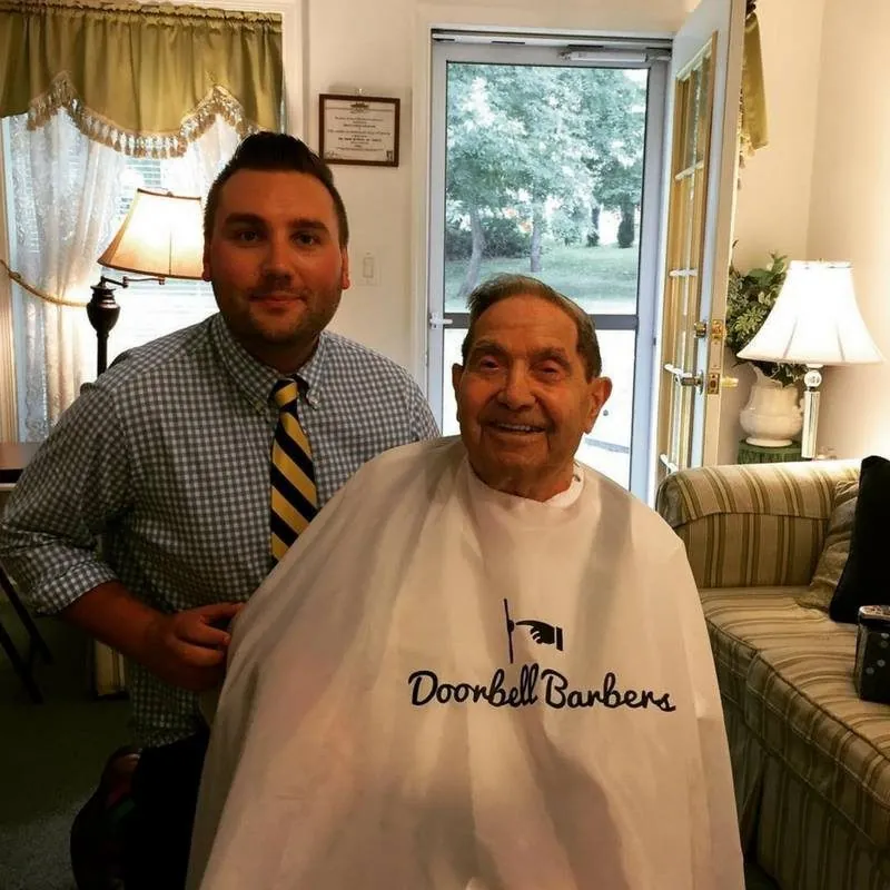 Christian Patrick with a senior client in a Doorbell Barbers cape during an in-home haircut
