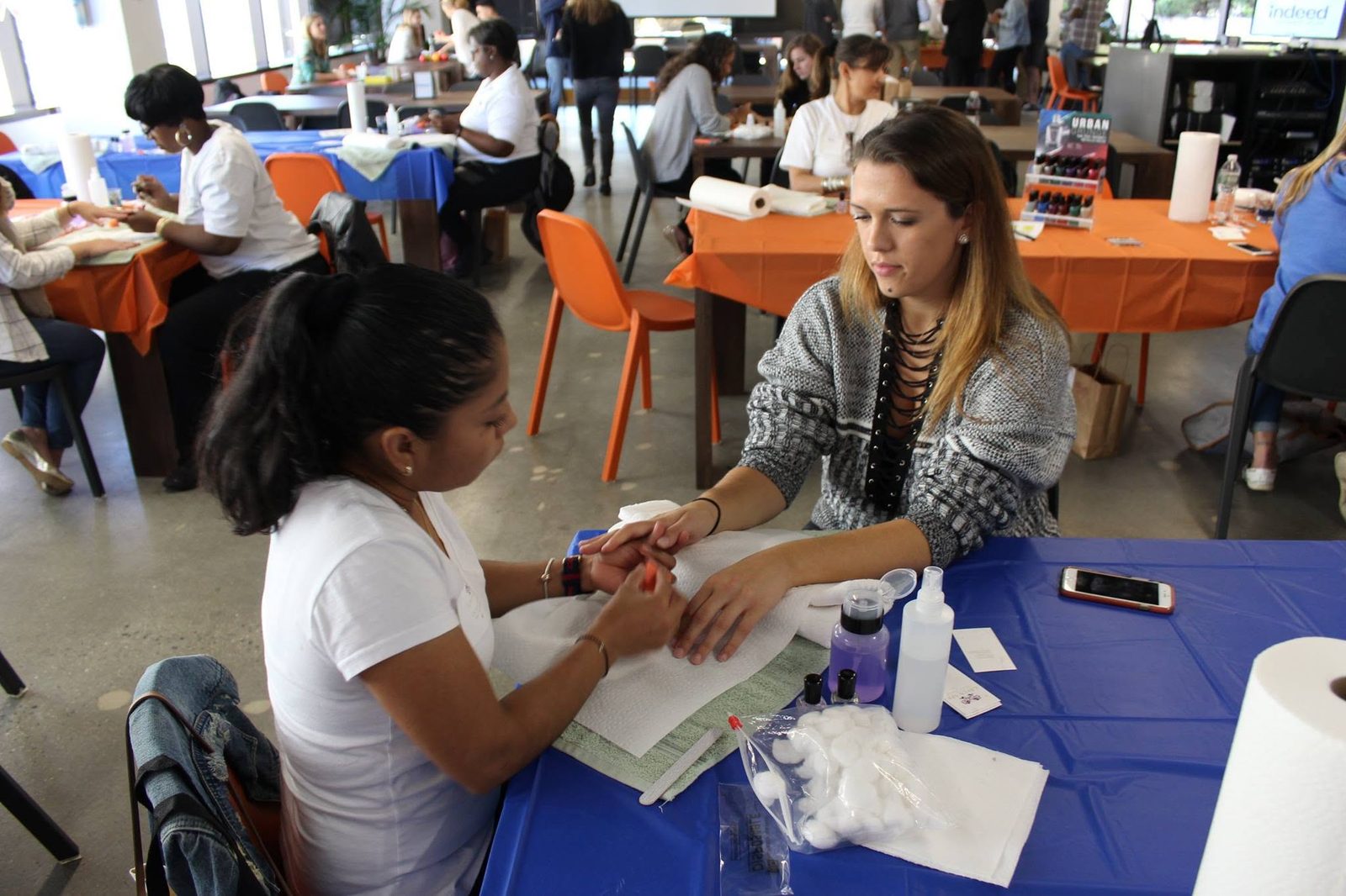 Rows of manicure stations serving employees in a company cafe during a wellness event