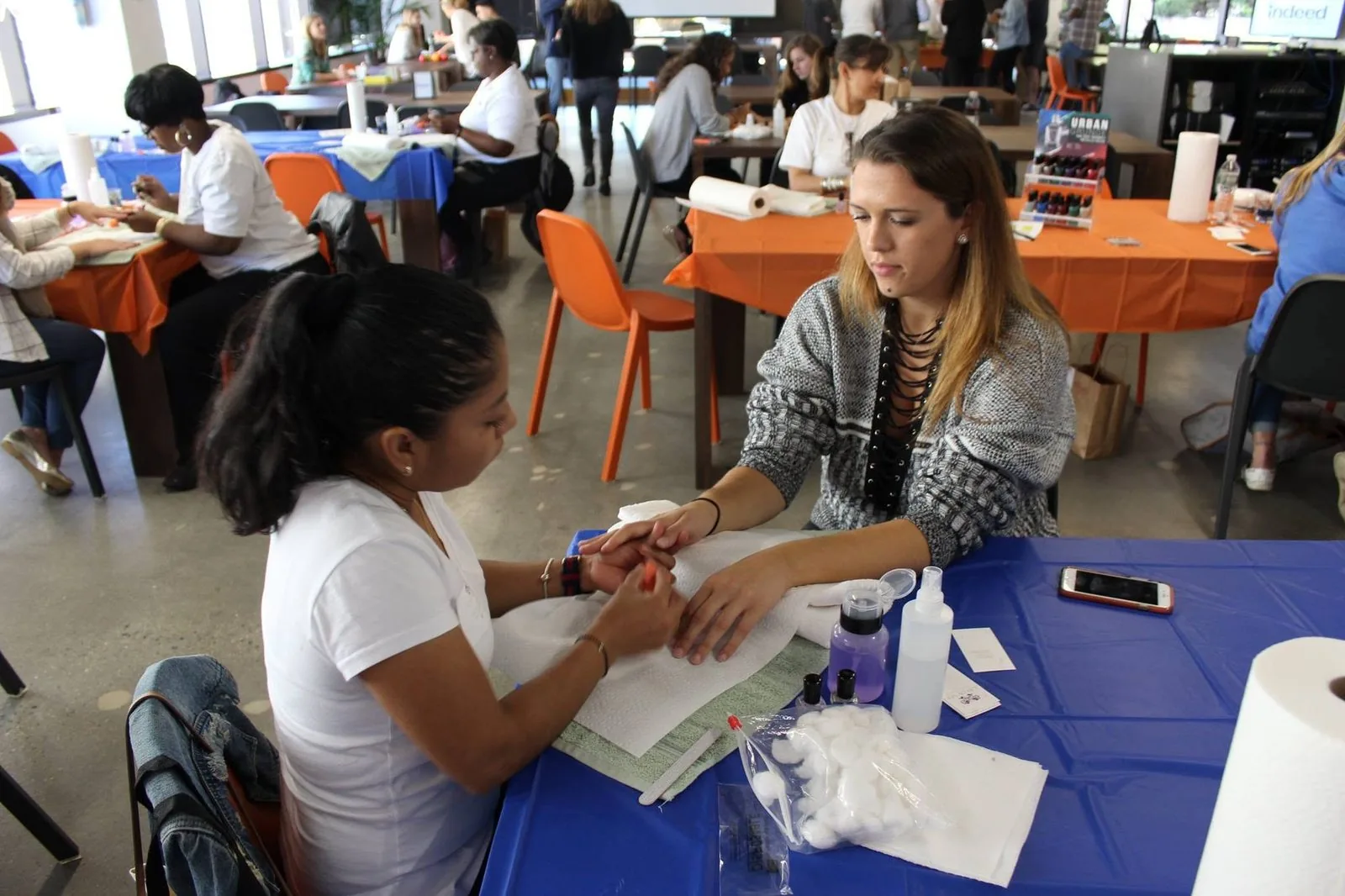 Rows of manicure stations serving employees in a company cafe during a wellness event