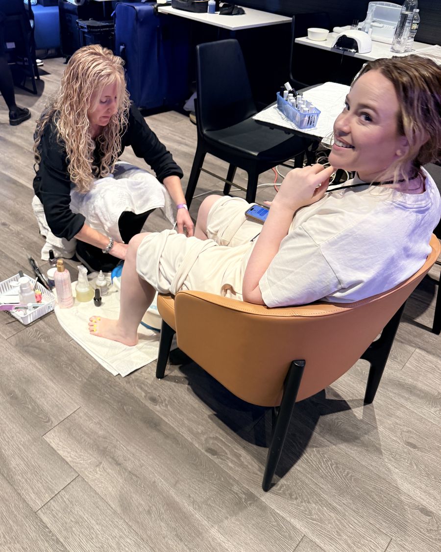 A Doorbell nail technician gives a smiling guest a pedicure in the backstage wellness suite
