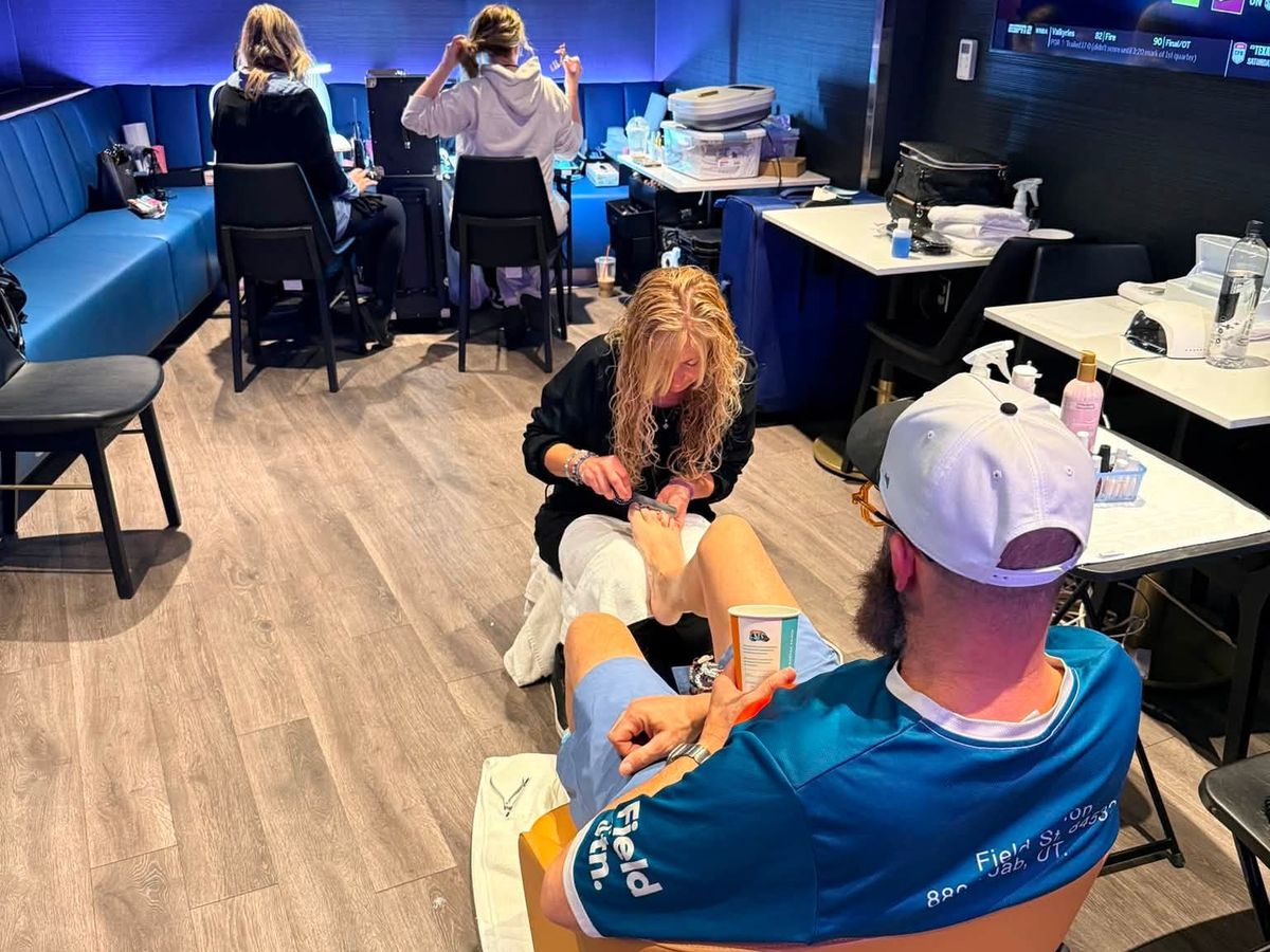 Inside the wellness suite at PeoplesBank Arena: a nail technician gives a touring crew member a pedicure while hair and nail services run at stations behind them